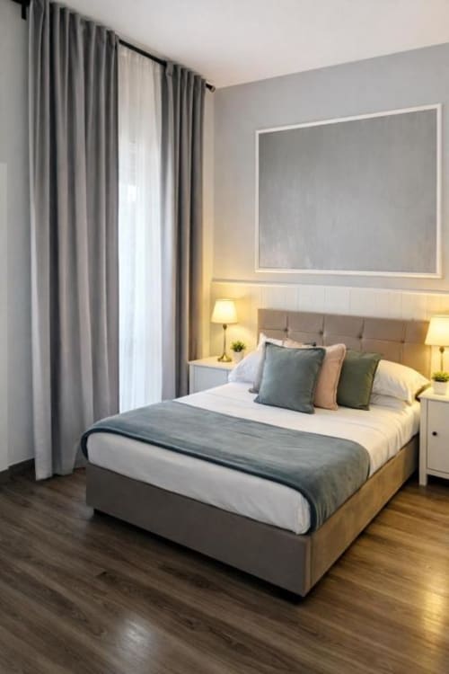 Camera moderna al Vatican Living Rome con letto matrimoniale, testata imbottita grigia, comodini, lampade e finestre dal pavimento al soffitto