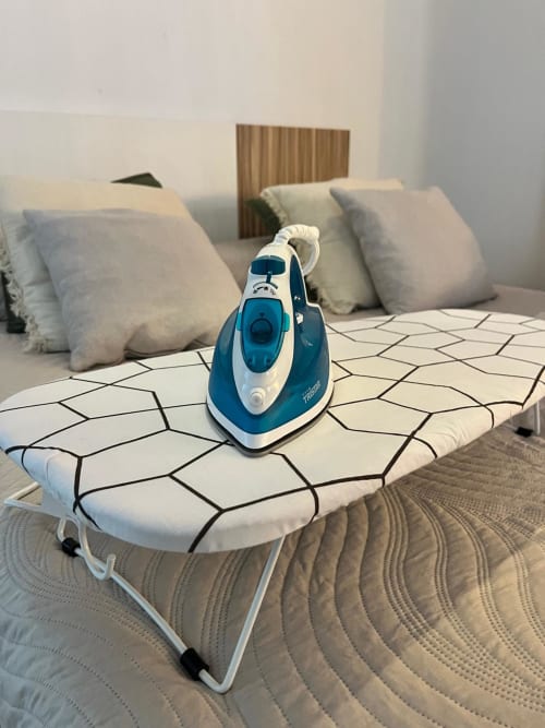 Plancha azul y blanca sobre tabla de planchar en el dormitorio del apartamento Casa Portalet, Feel Home Group, Xátiva