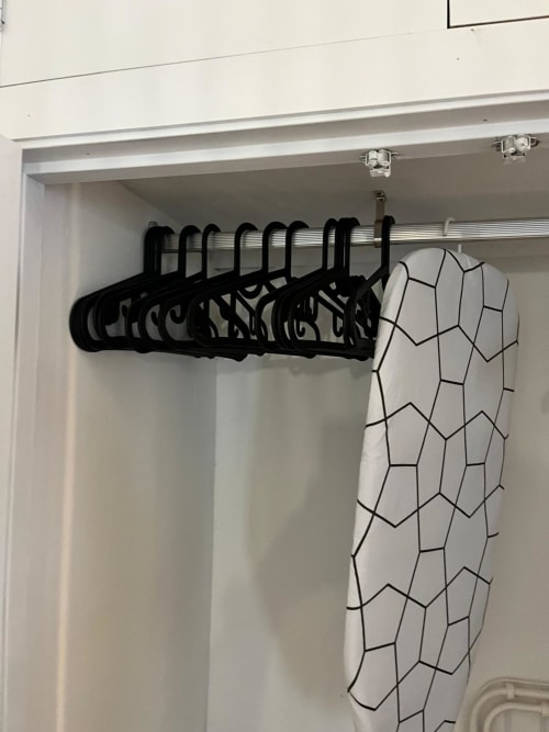 Perchas negras en varilla con cortina de ducha de patrón geométrico en el armario del apartamento Casa Portalet, Xativa