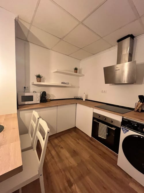 Cocina moderna en apartamento Casa Portalet, Xátiva con muebles blancos, encimeras de madera y electrodomésticos de acero inoxidable