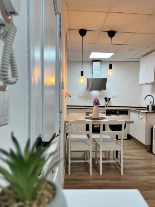 Cocina y comedor modernos en Casa Portalet, Xativa con muebles blancos, luces colgantes y equipamiento completo