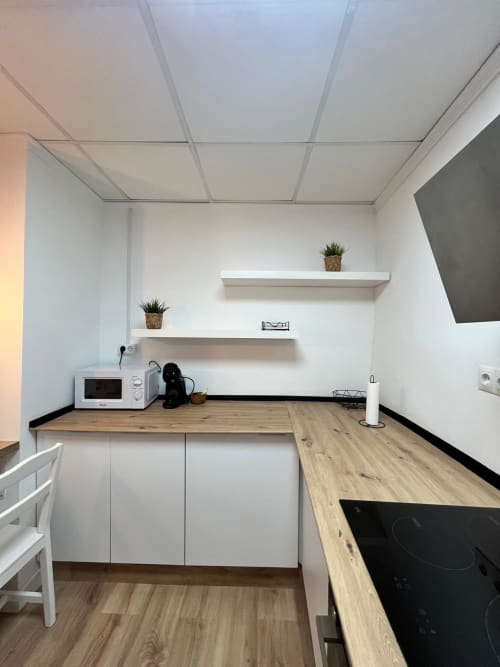 Cocina moderna con muebles blancos, encimeras de madera, estanterías abiertas y electrodomésticos en el apartamento Casa Portalet, Xativa