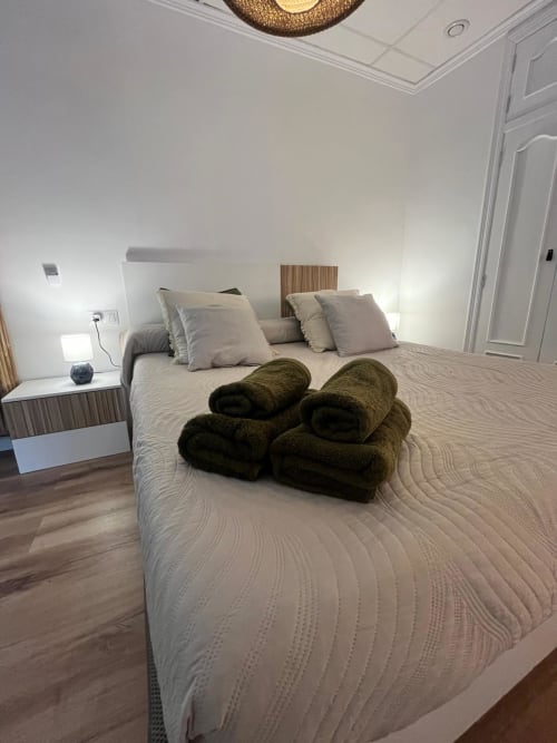 Dormitorio moderno en Casa Portalet de Xátiva con cama queen, toallas verde oliva y muebles contemporáneos