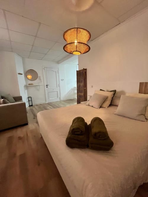 Dormitorio moderno en apartamento Casa Portalet de Xátiva con cama queen, lámpara de techo tejida y acogedora zona de descanso