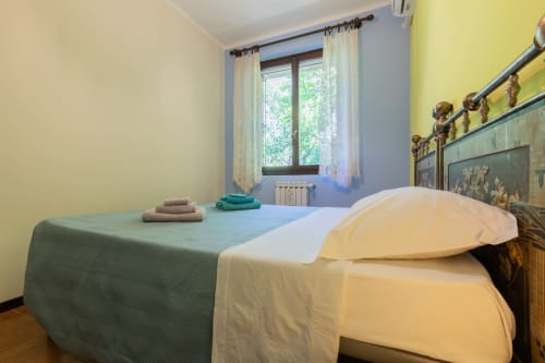 Camera luminosa al Prince Garda hotel di Salò con pareti blu e gialle, letto matrimoniale, finestra con tende e arredamento in legno