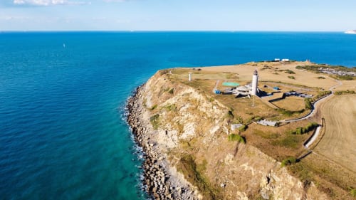 Vue aérienne du phare Les Logis d'Emma sur les falaises côtières spectaculaires de France dominant les eaux turquoise