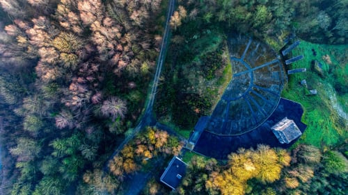 Vue aérienne de l'hôtel Les Logis d'Emma entouré de forêt, route sinueuse et bâtiments aux toits bleus en France