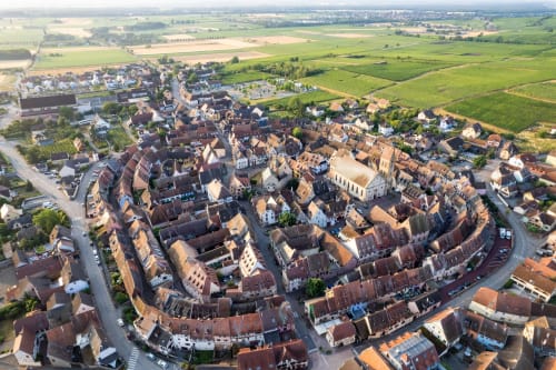 Vue aérienne d'une charmante ville médiévale française aux maisons aux toits rouges entourée de verdoyants champs agricoles