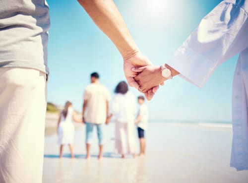 Familia tomada de la mano en la playa con cielo azul despejado en Barrosa Home, España