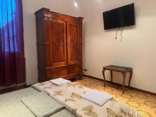 Camera da letto di BnB Fantasia Bologna con armadio in legno, materasso a terra, TV a parete e pavimentazione in sughero