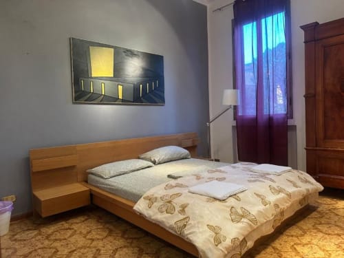 Camera moderna di BnB Fantasia Bologna con letto in legno, piumone farfalla e opera d'arte contemporanea