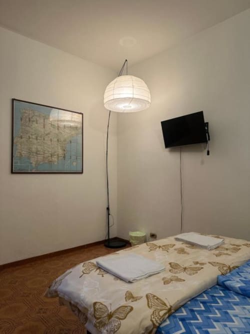 Camera accogliente al BnB Fantasia di Bologna con lampada a sospensione, mappa incorniciata, TV a parete e biancheria con motivi farfalle