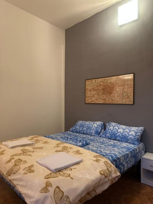 BnB Fantasia Bologna: Camera accogliente con due letti, biancheria blu a motivi, pareti beige, stampe di mappe incorniciate