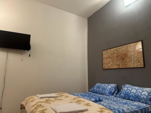 Camera BnB Fantasia Bologna con due letti, TV, cartina vintage e arredamento moderno