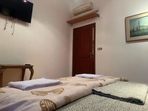 Camera pulita del BnB Fantasia Bologna con copriletto decorato, porta in legno scuro, climatizzatore e quadro con paesaggio urbano
