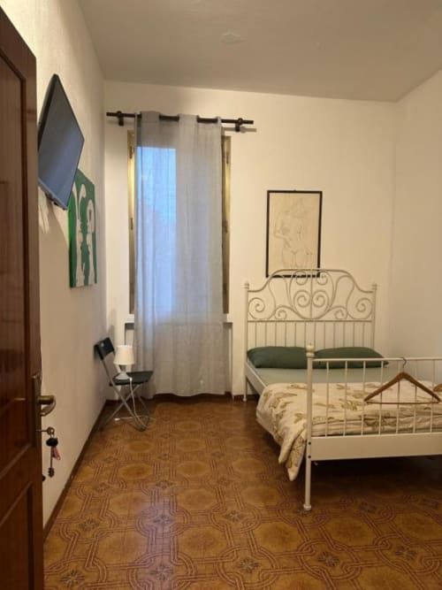 Camera accogliente di BnB Fantasia a Bologna con letto ornato, tende trasparenti e pavimento decorato