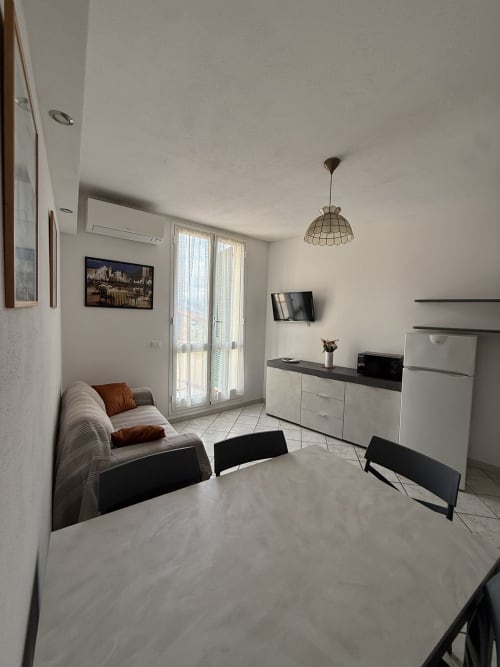 Moderno soggiorno dell'agriturismo Gli Ulivi con tavolo da pranzo, divano, TV e accesso al balcone a Maremo Sottano