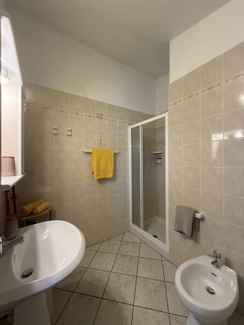 Spacious bathroom with dual sinks, walk-in shower, and tiled floors at Agriturismo Gli Ulivi apartment, Italy