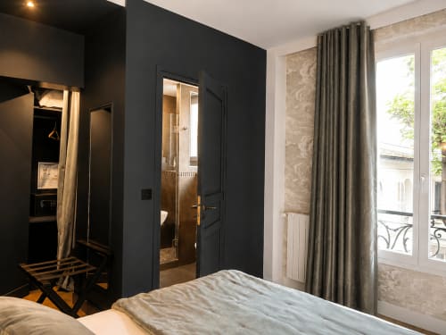 Chambre deluxe de l'Hôtel des Bains avec armoire noire, portes-fenêtres sur le jardin et élégants rideaux beige