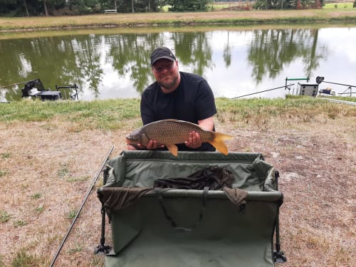 Man holding carp at Les 5 Etangs fishing pond in Brinon-sur-Sauldre, France