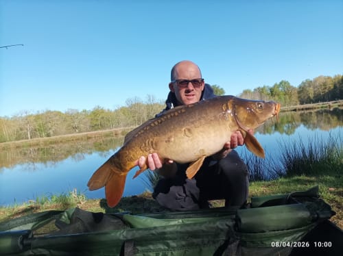 Angler holding large carp at Les 5 Etangs fishing retreat in Brinon-sur-Sauldre, France