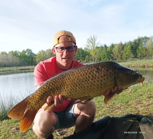 Angler displays large carp catch by pond at Les 5 Etangs, Brinon-sur-Sauldre
