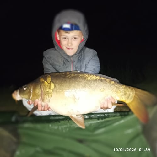 Young angler holding large carp at Les 5 Etangs fishing venue in Brinon-sur-Sauldre, France