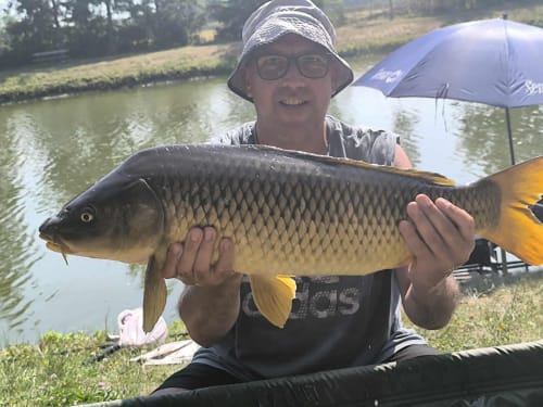 Angler displays large carp catch at Les 5 Etangs fishing pond in Brinon-sur-Sauldre, France