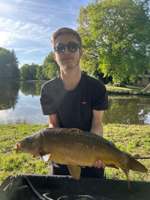 Man holding caught carp by pond at Les 5 Etangs, Brinon-sur-Sauldre