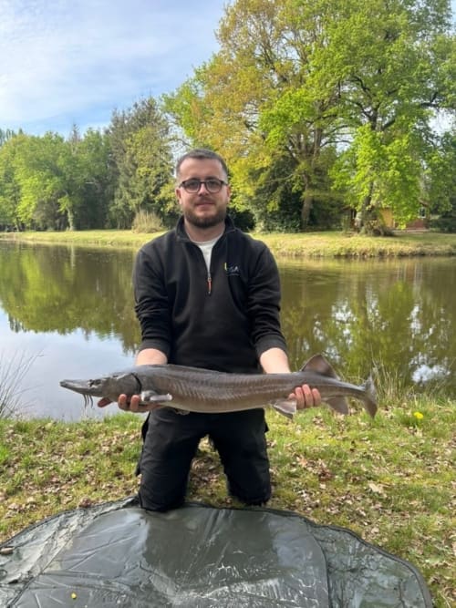 Man holding caught fish by pond at Les 5 Etangs, Brinon-sur-Sauldre