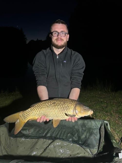 Guest holds prized carp catch at Les 5 Etangs fishing retreat in Brinon-sur-Sauldre, France