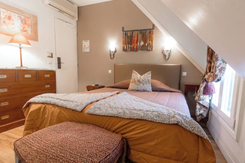 Cozy bedroom at Hôtel des Bains with warm tones, wooden furniture, and sloped ceiling in classic room style
