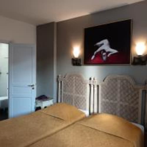Modern hotel bedroom at Hôtel des Bains with bed, upholstered headboard, framed artwork, and city view