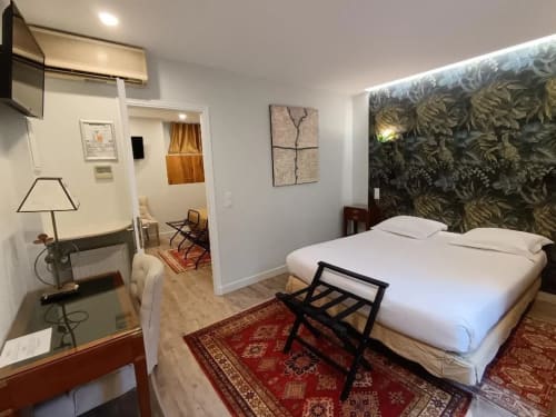 La Suite de l'Hôtel des Bains avec lit queen-size, tête de lit en papier peint de fougères, bureau et accès à la vue sur le jardin
