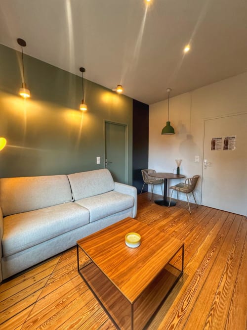 Séjour du studio O LIT à Trouville-sur-Mer : canapé gris, table en bois, coin repas et luminaires suspendus