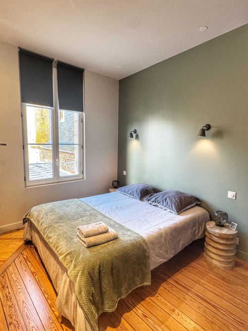 Chambre moderne du studio O LIT à Trouville-sur-Mer avec lit queen-size, mur d'accent vert et accès au balcon