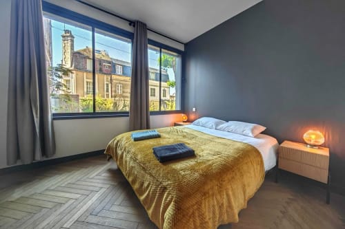 Chambre contemporaine à l'O LIT Loft de Trouville-sur-Mer avec vue sur le jardin, literie jaune et murs gris anthracite