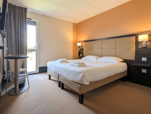 Chambre moderne à La Verriaire à Chanverrie avec lit queen-size, mur d'accent orange et accès à un balcon