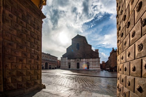 Piazza storica di Bologna con chiesa vista dalla struttura ricettiva BnB Fantasia, ciottoli bagnati e architettura rinascimentale sotto cielo nuvoloso