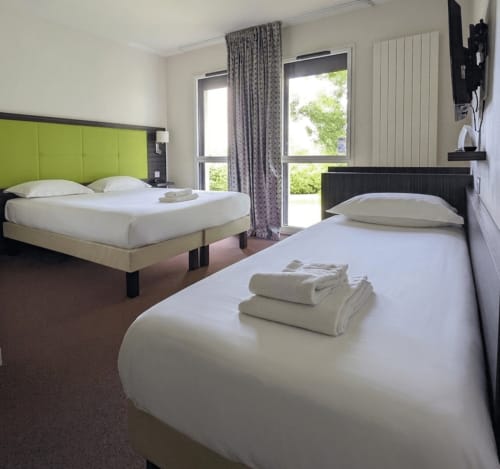 Chambre moderne de La Verriaire avec deux lits, tête de lit vert citron, vue sur la verdure de Chanverrie