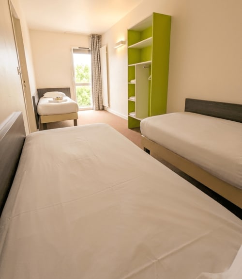 Chambre twin de l'hôtel La Verriaire à La Verrie avec lits blancs, meuble de rangement vert et fenêtre