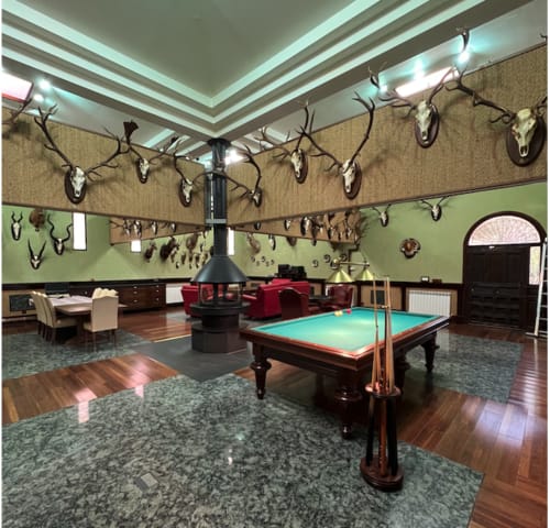 Sala de juegos rústica en Chalets Junto A Puy Du Fou con billar, trofeos de caza, chimenea y asientos rojos en Argés