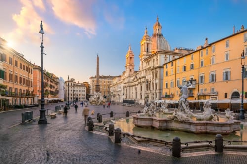 Piazza Navona a Roma con fontane barocche, edifici storici e cupola della chiesa di Sant'Agnese al tramonto