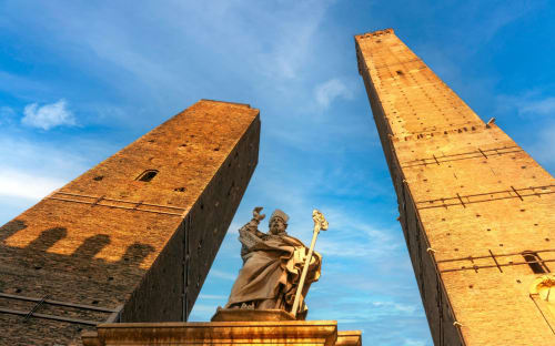 Le iconiche torri medievali di Bologna e statua sotto il cielo azzurro, vicino a BnB Fantasia