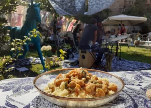 Piatto di curry di ceci nel giardino del Mappamondi B&B a Venezia, con ospiti e ombrelli sullo sfondo