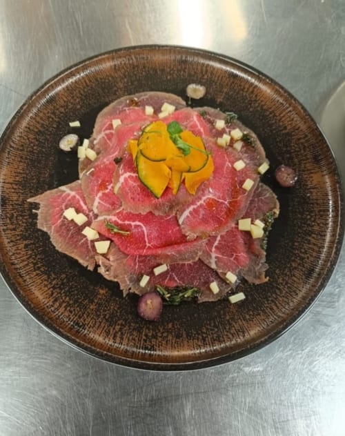 Elegante piatto di carpaccio a Mappamondi Venezia - manzo affettato finemente con peperoni gialli, capperi e formaggio