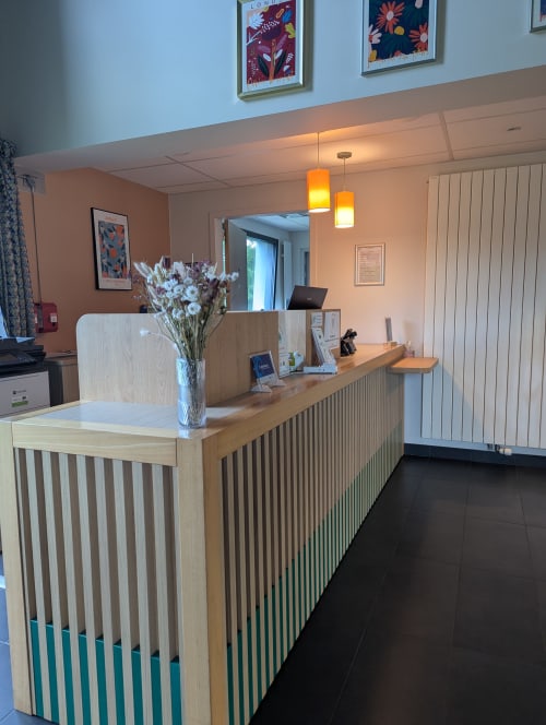 Réception moderne de l'hôtel La Verriaire avec boiseries, fleurs fraîches et éclairage chaleureux à Chanverrie