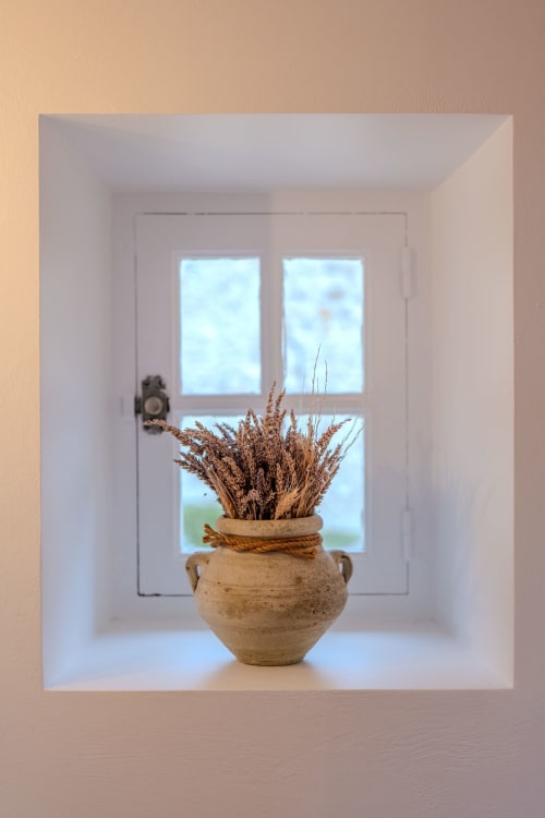 Rustic terracotta vase with dried wheat in a white niche at Mas Bella Cortis, La Garde-Adhémar