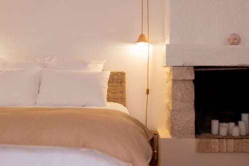 Cozy bedroom at Mas Bella Cortis B&B in La Garde-Adhémar with warm pendant lighting and fireplace