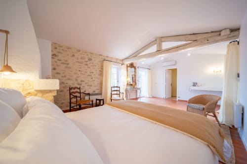 Spacious master bedroom at Mas Bella Cortis B&B in La Garde-Adhémar with exposed beams, white bedding, and elegant
